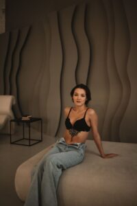 Brunette woman in casual attire sitting in stylish room with artistic decor.