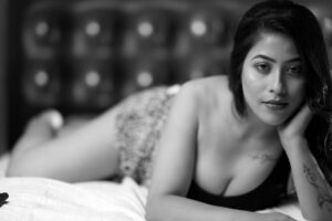 A stylish monochrome portrait of a young woman lying on a bed, exuding elegance.